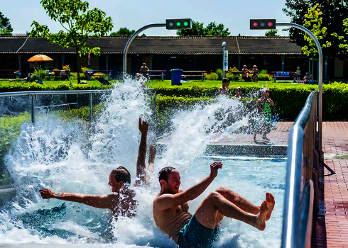 Zwei Personen rutschen lachend eine Breitwellenrutsche herunter.