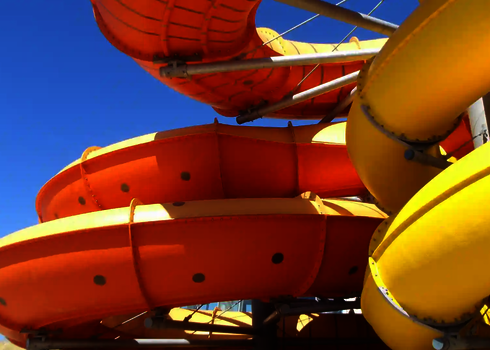 Detailansicht der gelben und orangen Family Twister Wasserrutsche bei blauem Himmel.