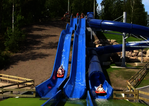 Blaue Wasserrutschen mit rutschenden Personen, die einen Hang herabführen.