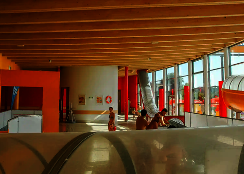 Im Hallenbad führt eine transparente Wasserrutsche durch die Fensterfassade nach außen.