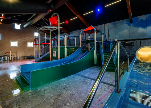 Kinderbereich eines Hallenbades mit Wasserrutschen und weiteren Wasserspielgeräten.