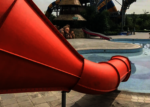 Ein roter Crazy Cone mündet in ein leeres Becken in einem tropisch gestalteten Park.