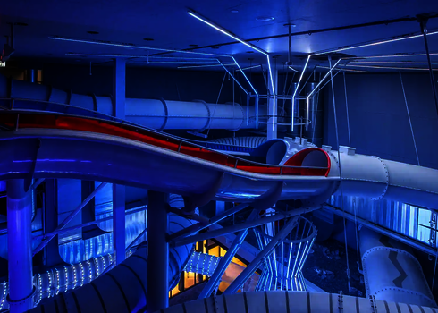 Blau beleuchtete Startplattform der Raft Racer Doppelrutsche mit Lichtinstallationen.