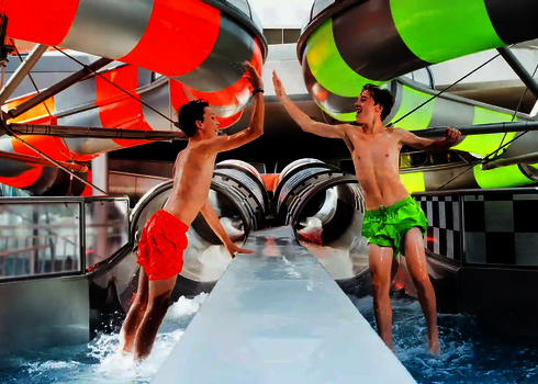 Zwei Jugendliche geben sich nach dem Rutschen High-Five im Auslaufbecken.