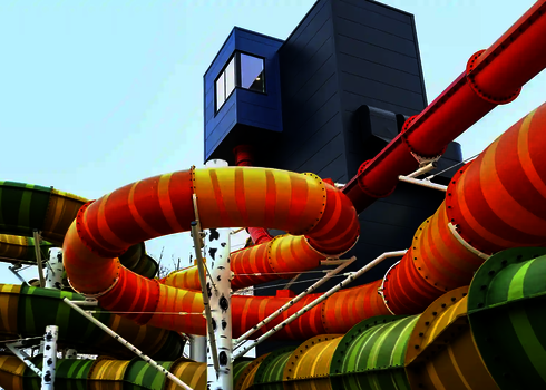 Mehrere farbige Rutschen der Family Twister Variante winden sich bunt gemustert um den blauen Startturm.