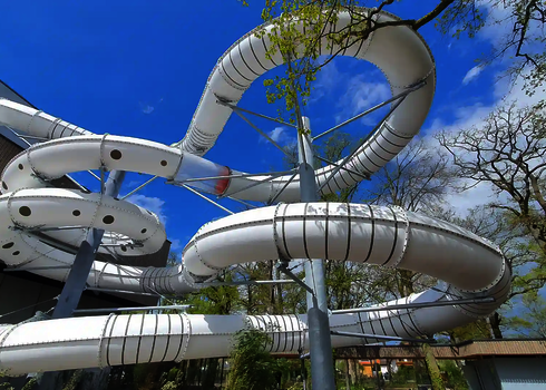 Lange RR1400 Wasserrutsche die unter freiem, blauen Himmel neben einem Gebäude steht.