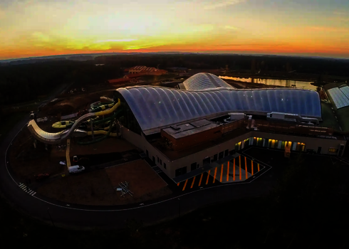 Panoramaaufnahme bei Sonnenuntergang mit der auffälligen Boomerang-Rutsche außen.