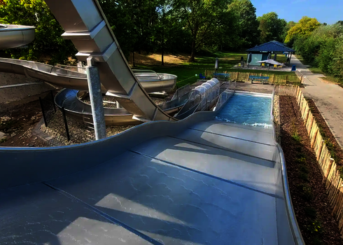 View from above of wide slide with landing pool, next to it further stainless steel slides.