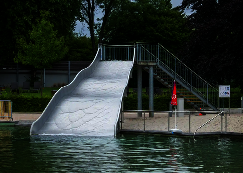 Breitwellenrutsche, die in einem Schwimmbecken endet, im Hintergrund der Treppenaufgang.
