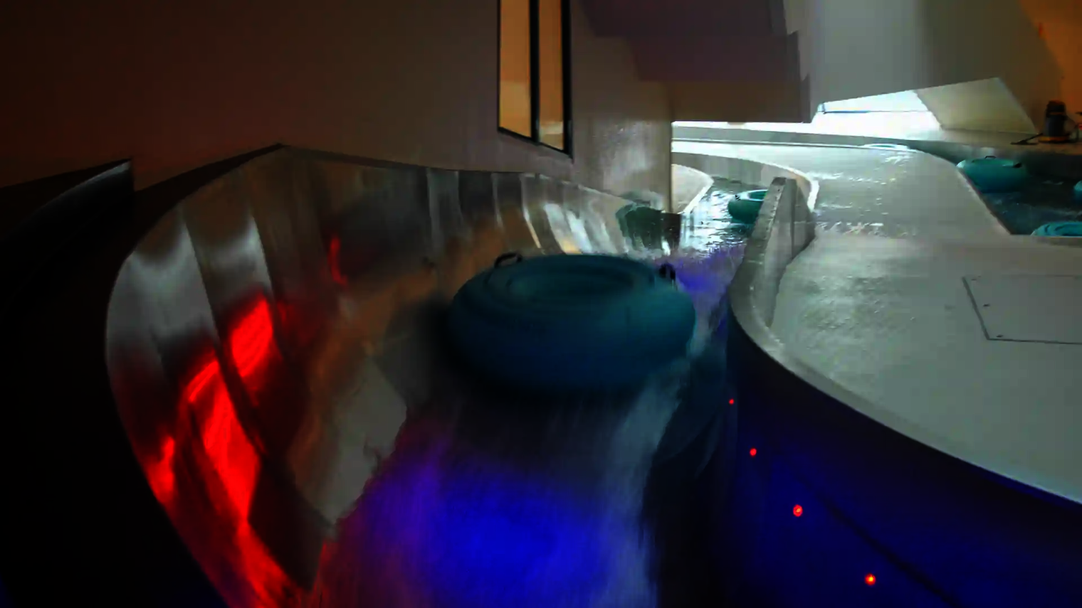 Rutschreifen gleiten durch die Lazy River Wasserrutsche mit bunter Beleuchtung.