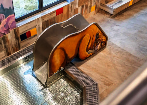  Blick von oben auf die gelbe Bärenrutsche am Kinderbecken mit flachem Wasser.