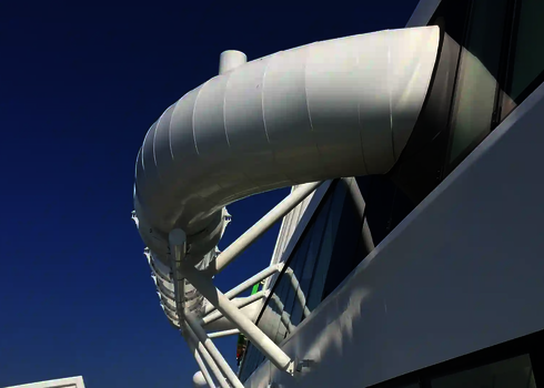 Eine weiße Wasserrutsche befindet sich außerhalb des Schiffes getragen von weißen Stahlträgern.