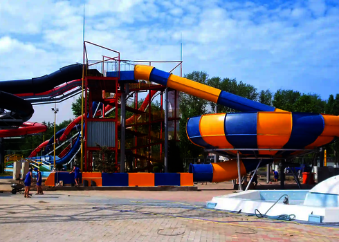 Freizeitbad unter blauem Himmel mit bunter Reifenrutsche.