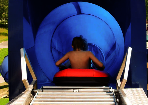 Kind sitzt im Reifen im blauen Startbereich einer Harakiri Wasserrutsche.