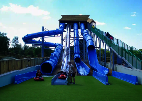 Mehrere blaue Rutschen müden auf grünen Boden.