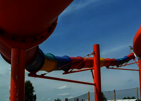 Aufnahme einer bunten Röhrenrutscht die von orangefarbenen Stahlstützen getragen wird.