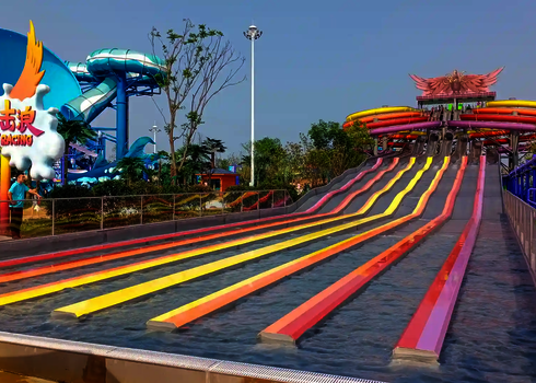 Unterschiedliche Rutschbahnen des Matracers in pink und gelb Tönen in einem Wasserpark.