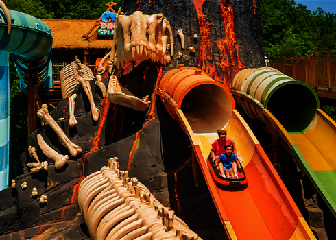 Tunnelöffnungen von zwei Harakiri Rutschen in einem Freizeitpark mit Dinosaurier-Theme.