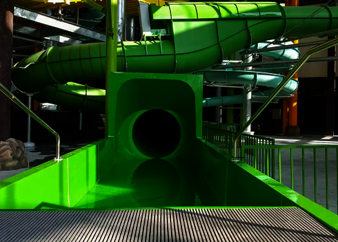 Green slide with round tunnel opening and surrounding tube slide.