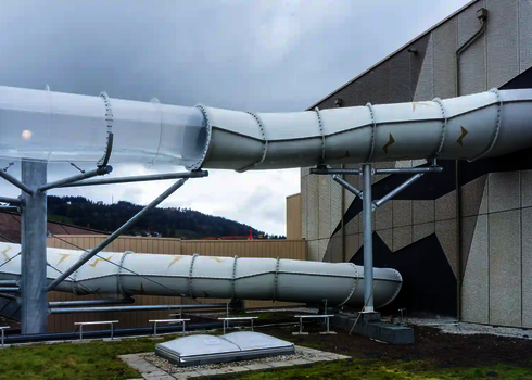 Acryl-Elemente in einer weißen Wasserrutsche an der Außenwand eines Gebäudes.