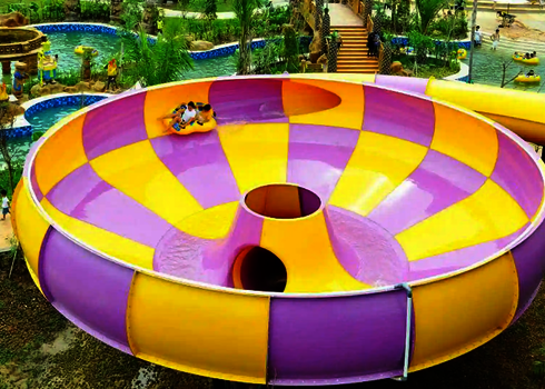 Raft Bowl in einem Wasserpark, umgeben von Besuchern, Palmen und weiteren Rutschen.