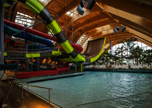 Die Boomerang-Rutsche endet in einem großen Auffangbecken in tropischer Badelandschaft.