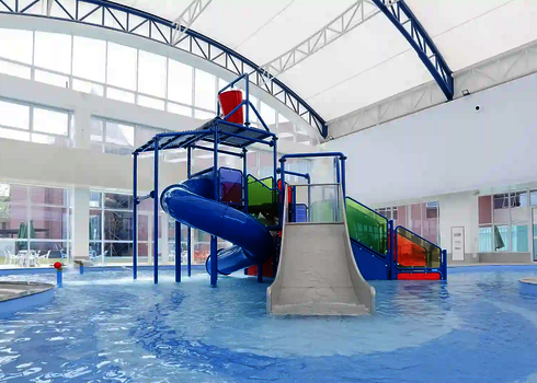 Bunte Wasserspielstruktur in einem weißen Hallenbad.