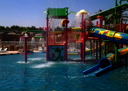 Wasserpark mit buntem Kinderbereich und verschiedenen Wasserspielen in einem Schwimmbecken.