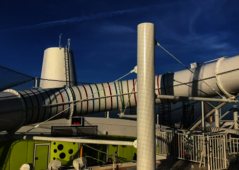 Bunte Wasserrutsche mit roten, blauen und grünen Streifen auf Schiffdeck.