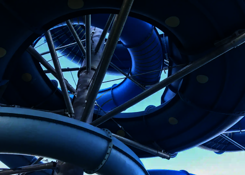 Blick von unten auf die verschlungenen Kurven der blauen Family Twister Reifenrutsche.