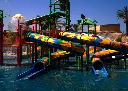 Wasserspielstruktur mit bunten Rutschen, die in einem blaues Schwimmbecken führen.
