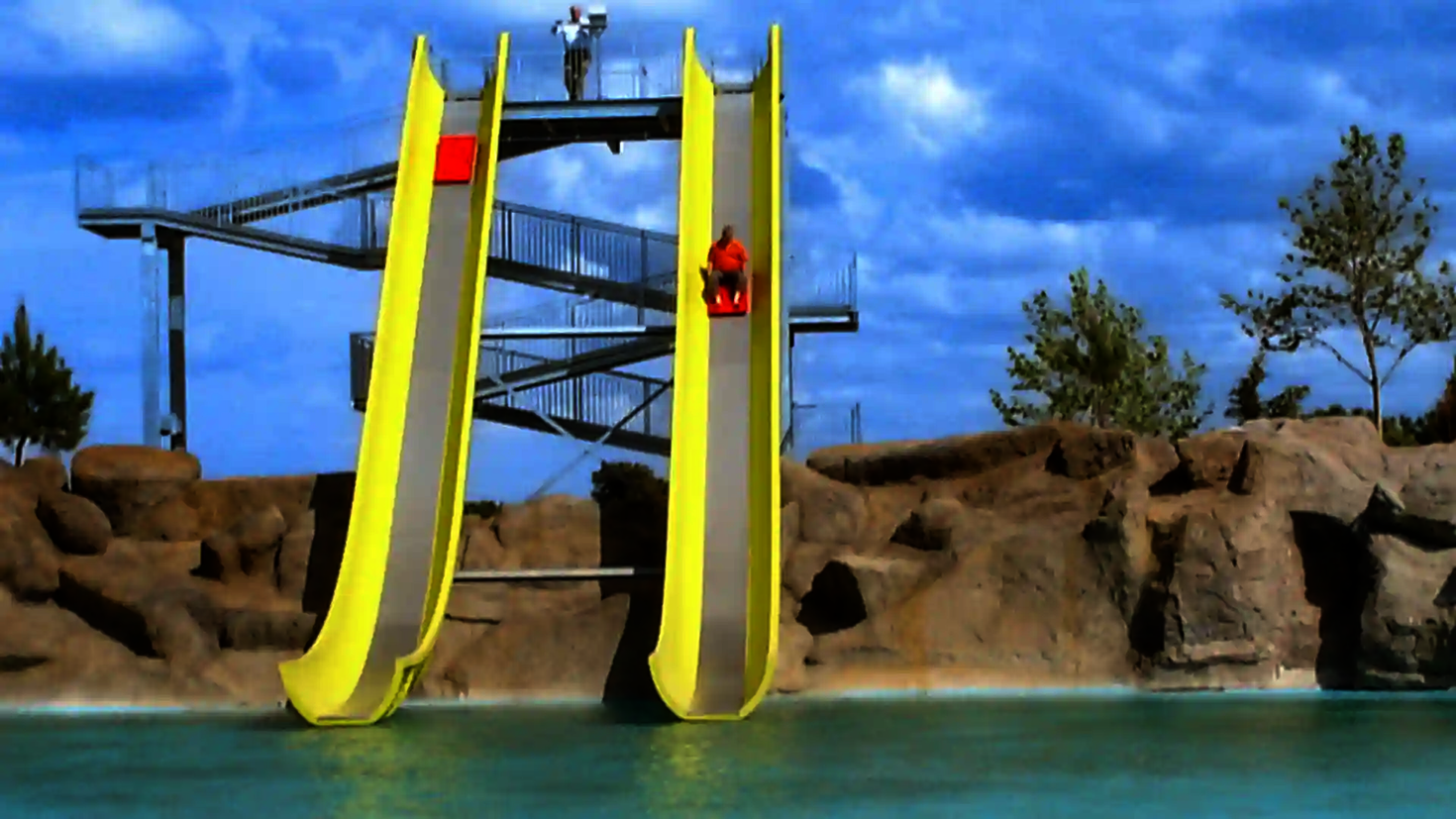 Zwei gelbe Bahnen des Aqua Shuttle mit einer Person auf einer roten Rutschmatte.