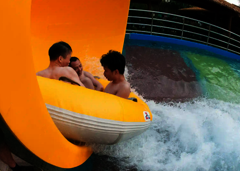 Seitenansicht, wie drei Personen aus einer RR2700 Rutsche im Auslaufbecken ankommen.