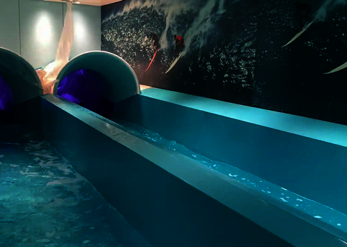 Zwei Body Racer Rutschen mit violettem Licht im Auslaufbecken eines Schiffes.