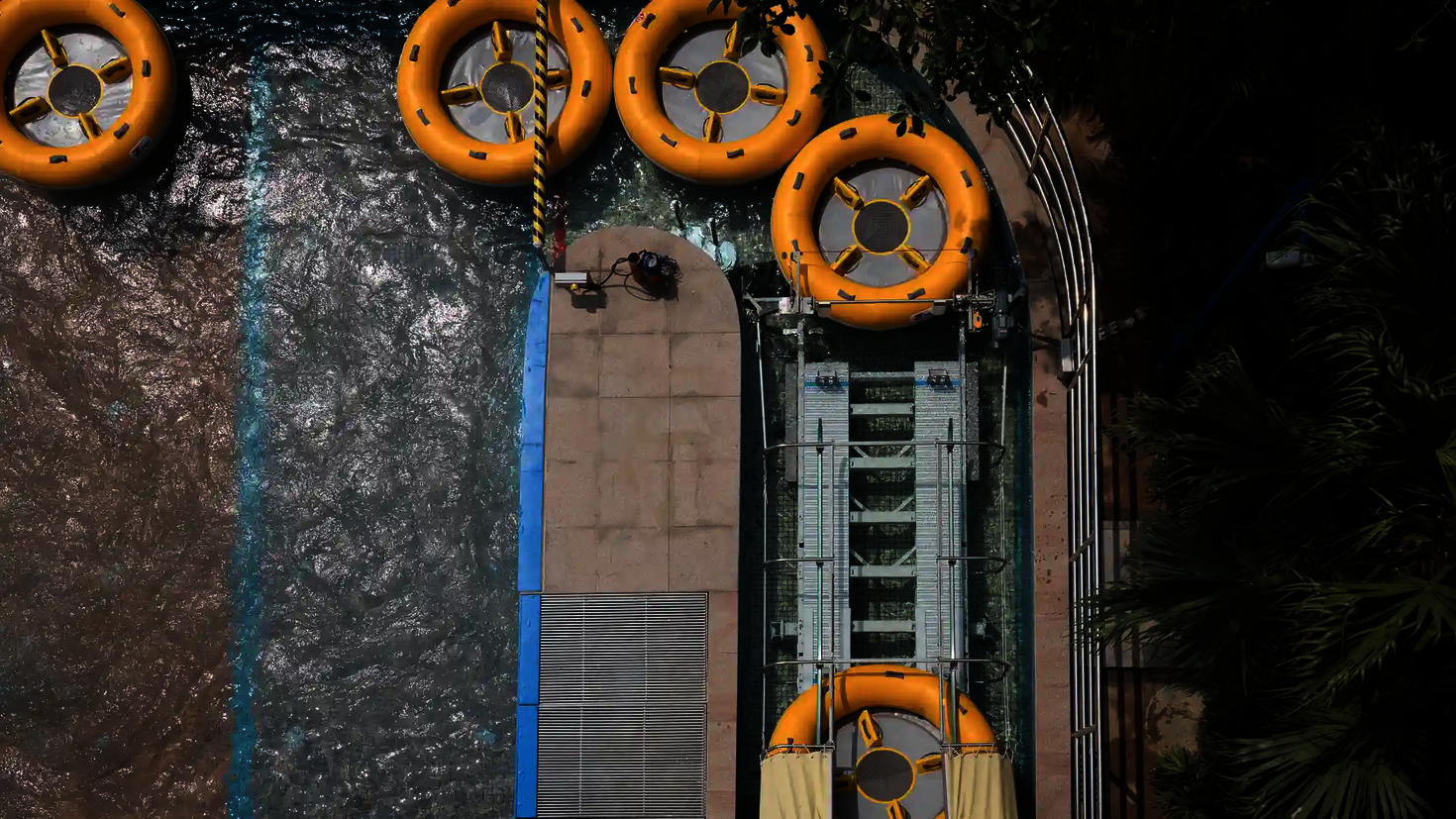 Luftaufnahme zeigt das Ende der Wasserrutsche mit mehreren gelben Rutschreifen im Becken.