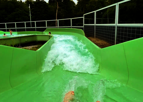 Aus der Nutzerperspektive: Rutschenfahrt durch eine Kurve mit starker Wasserströmung.