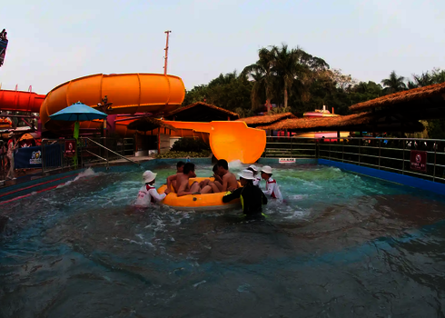 Blick auf das Auslaufbecken in einem Wasserpark, mit Menschen im Rutschreifen und Sicherheitspersonal.