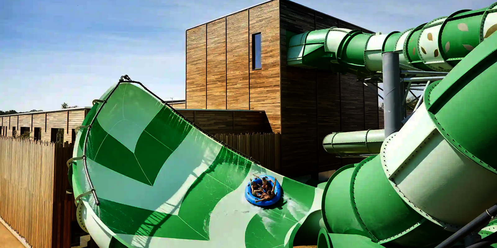 Vier Personen rutschen auf einem Rutschreifen die grüne Lotus Wasserrutsche hinab.