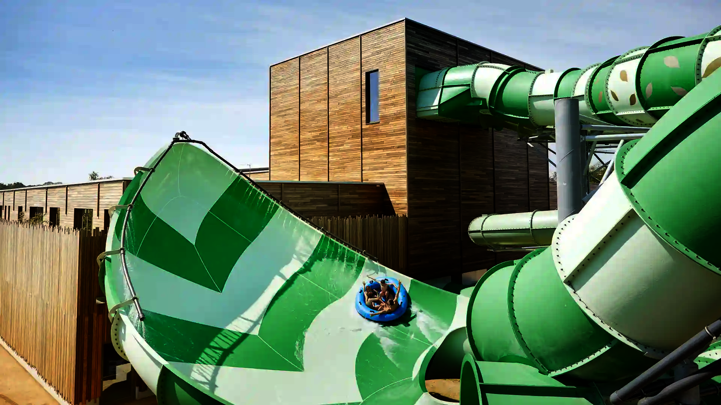 Vier Personen rutschen auf einem Rutschreifen die grüne Lotus Wasserrutsche hinab.