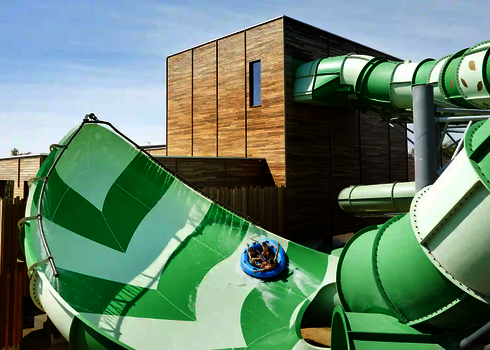 Vier Personen rutschen auf einem Rutschreifen die grüne Lotus Wasserrutsche hinab.