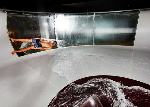 Innenansicht einer rot-weißen Body Bowl Wasserrutsche mit einer rutschenden Person.