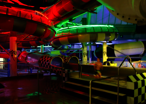 Zwei leuchtende Body Racer Auslaufbecken unter bunten Wasserrutschen.