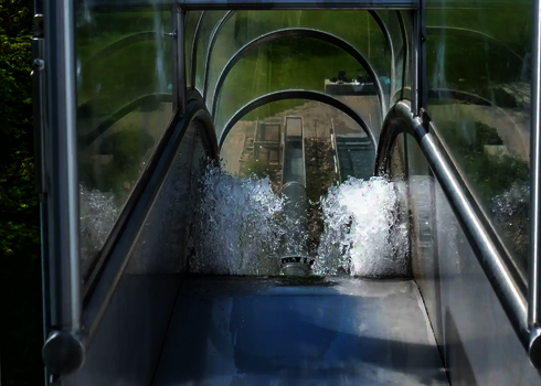 Blick vom Start einer Freifallrutsche mit transparentem Einstieg und Wasserausstoß.