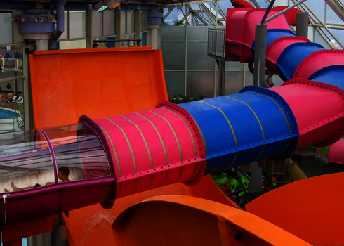 Pink-blaue Family Twister Wasserrutsche mit durchsichtigem Abschnitt im Innenbereich.