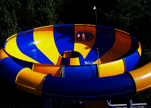 Seitlicher Blick auf den Trichter einer Raft Bowl Reifenrutsche, Bäume im Hintergrund.