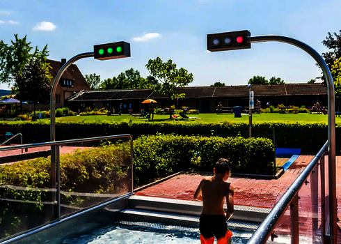 Kind steht im Auslaufbecken eines Freibades, mit Sensorampeln.