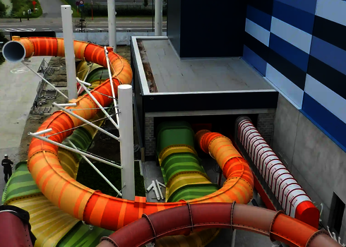 Mehrere bunte Wasserrutschen befinden sich im Bau außerhalb eines Gebäudes.