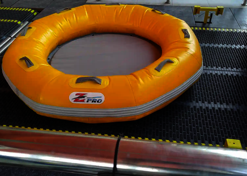 Gelber Rundboot-Rutschreifen liegt auf einem schwarzen Förderband mit Sicherheitsmarkierungen.