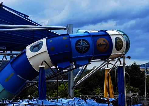 Geschlossene Rutsche mit Tageslichtmotiven wie Kompass, Anker und Steuerrad auf blauen und weißen Segmenten.