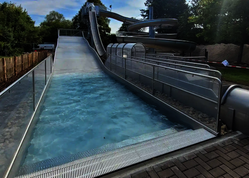 Empty slide chute with water basin and glass protective walls on the outside.